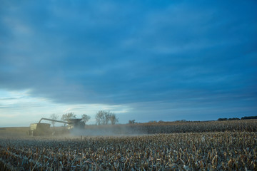 Dusty wheat stubble combine harvester at sunset