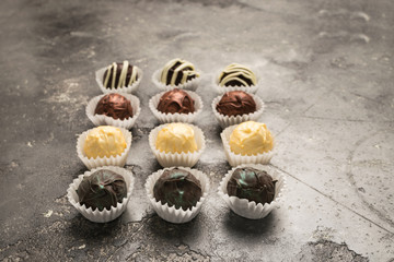 A set of chocolates from different chocolate lies on a gray background. Assorted white and dark chocolate