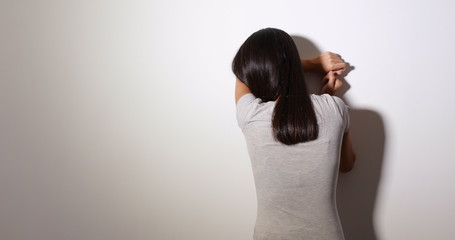 Woman cry and standing against the wall