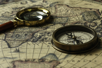 Retro compass with old map and magnifier