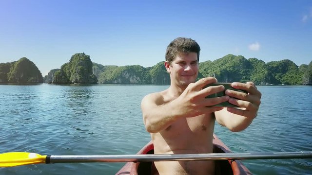 Joyful Man Makes Selfie on Phone in Kayak among Quiet Bay