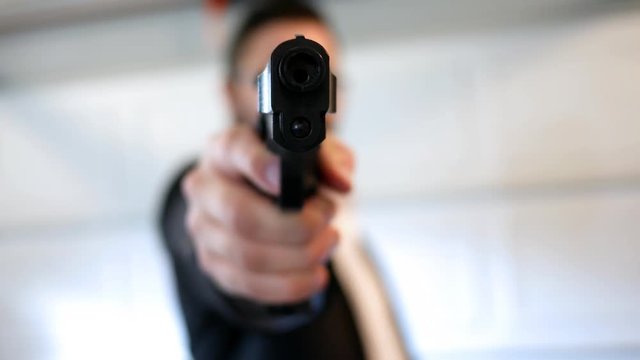 Secret Agent raises firearm pistol at camera in hangar bay