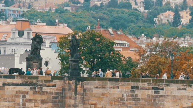 Prague Charles Bridge on Vltava River on which crowds of tourists stroll