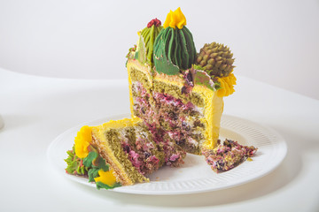   Yellow biscuit cake decorated with a green cream in the form of flowers and cactus in a light kitchen