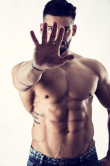 Fototapeta premium Defiant stern man making a Halt or Stop gesture holding his hand extended to the camera denying access, calling for a halt or finish, a stop, or indicating he has had enough and to go away