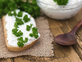 A piece of bread with curd cream and spoon dark wood on a rustic table.