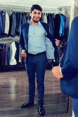 Adult guy is trying on jacket in front of the mirror