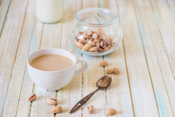 Obraz na płótnie Canvas Coffee with milk and pistachios on wooden table