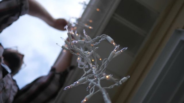 Brave Father Hanging Icicle Lights On A Roof Of A Home On Ladder ALT