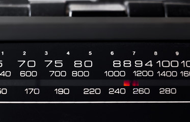 Black dial and red arrow of a portable radio close-up.
