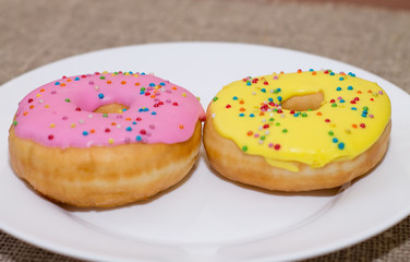 Donuts with a glaze on a white plate. Colored sweet donuts