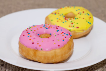 Donuts with a glaze on a white plate. Colored sweet donuts