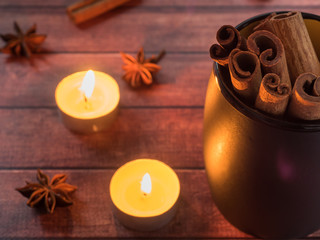 Black ceramic Cup with cinnamon on dark wooden table with candles