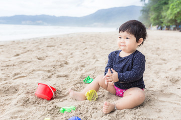Asian cute girl happy and playing with sand toy on the beach.