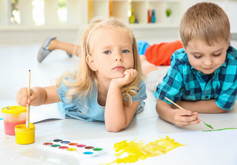 Children lying on floor in light room and painting