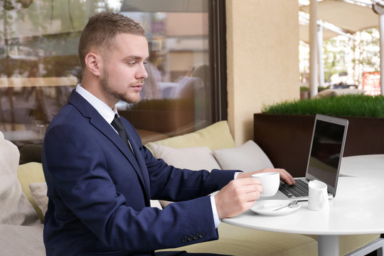 Handsome businessman working with laptop in street cafe