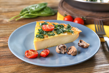 Piece of tasty frittata with spinach on plate