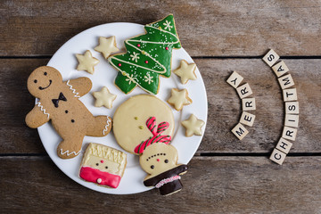 Festive Christmas Cookie and New Year in the shape of Christmas tree, Gingerbread man, snowman, Snowflake, star in White plate on wooden table