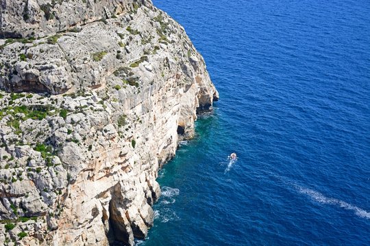 View looking down at Blue Grotto Cove with tourists in a tour boat, Blue Grotto, Malta.