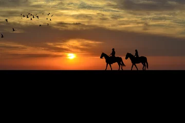Abwaschbare Fototapete Reiten Ein Paar auf einem Reiter bei Sonnenuntergang