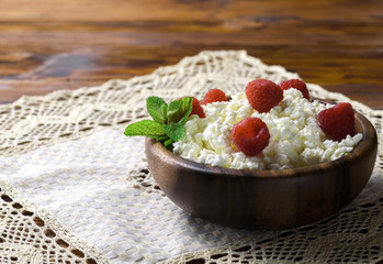 Cottage cheese with fresh raspberry in a wooden bowl on old wooden background with copy space for your text. Top view