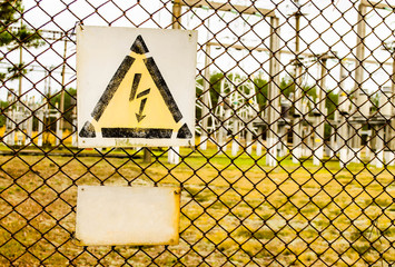 Fenced fence and warning sign dangerous high voltage. Electrical power plant with High Voltage sign in a fence.