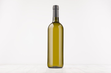 Green wine bottle with white wine on white wooden board, mock up. Template for advertising, design, branding identity.