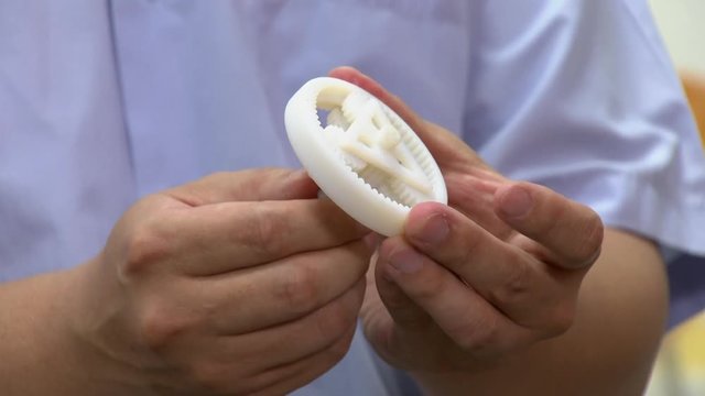 A man is spinning with his hands a planetary gear printed with 3D technology.