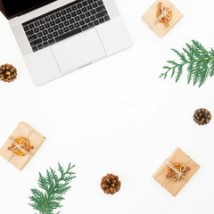 Laptop with Christmas gift box and pine cone on white background. New year composition. Top view. Flat lay
