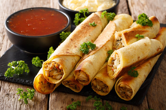 Tasty taquitos with chicken and two sauces close-up. horizontal