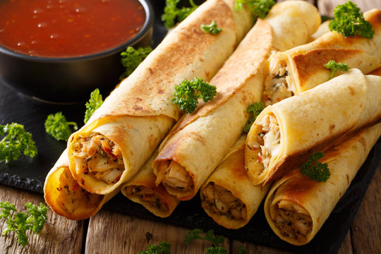 Mexican taquitos with chicken and chili sauce close-up. horizontal