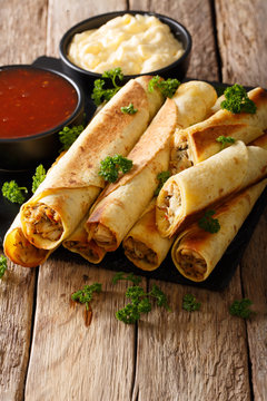 Mexican taquitos with chicken and sauces close-up. vertical