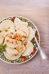 Dumplings, filled with potato and served with salty caramelized onion. Varenyky, vareniki, pierogi, pyrohy - popular dish in East Europe. View from above, top studio shot, vertical