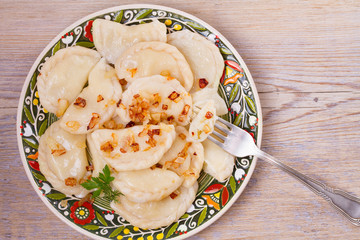 Dumplings, filled with potato and served with salty caramelized onion. Varenyky, vareniki, pierogi, pyrohy - popular dish in East Europe. View from above, top studio shot, horizontal