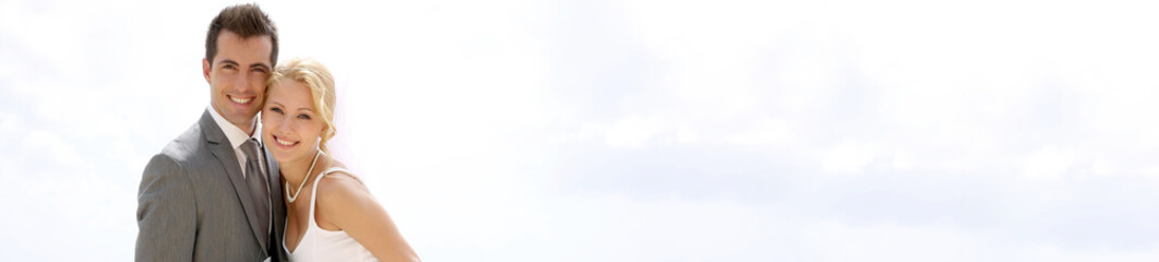 Bride and groom sitting on a fence by the beach - banner template web