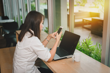 Beautiful woman using smartphone searching information and laptop