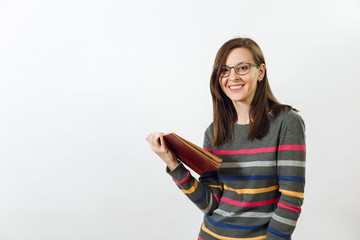 Fototapeta premium Beautiful European young brown-haired woman in glasses for sight dressed in casual dark grey longsleeve with colorful stripes, standing with book on a white background. Reading and studying concept.