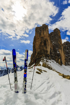 Mountaineer backcountry ski equipment in spring snow.  In background blue cloudy sky and shiny sun and Tre Cime, Drei Zinnen in South Tirol, Dolomites, Italy. Adventure winter extreme sport.