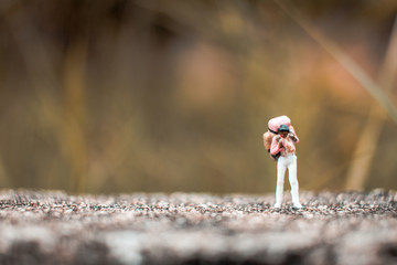 Miniature Backpacker standing on the concrete wall with natural background