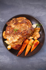 Roasted ham with vegetables on grey rustic background, view from above, top, vertical