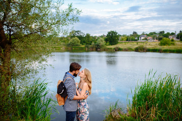 A picture of a young romantic couple kissing. Happy woman and man enjoy beautiful lake and good weather