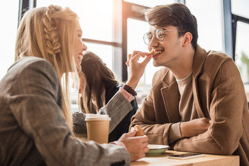 Girlfriend giving piece of croissant to boyfriend