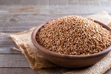 Buckwheat groats in  bowl on wooden background