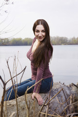 Beautiful Girl sitting on a log at the beach