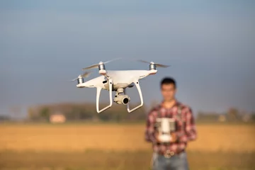 Fotobehang Farmer navigating drone above farmland © Budimir Jevtic