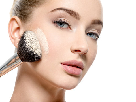 Fototapeta Girl applies  powder  on the face using makeup brush.