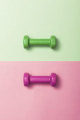 two dumbbell on the color(green, pink) paper background.