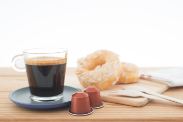 Cup of espresso, espresso capsule and bakery on wooden table.