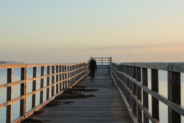 Fototapeta na wymiar athletic old senior with grey hair and dumbbells walk along a pier