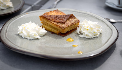 Kouign-amann is a typical dessert from brittany France made of butter. The desert is served on a plate with whipped cream on both sides.